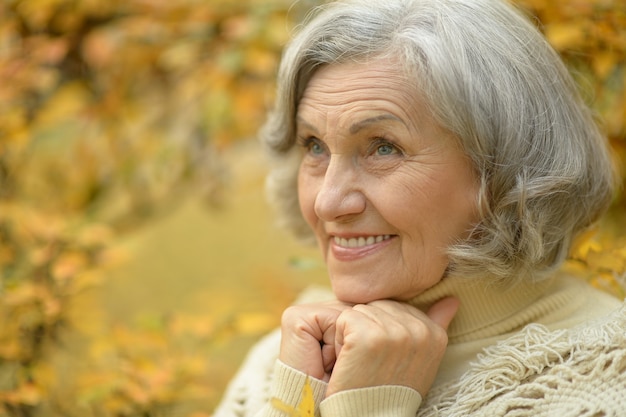 Happy beautiful senior woman in the autumn park