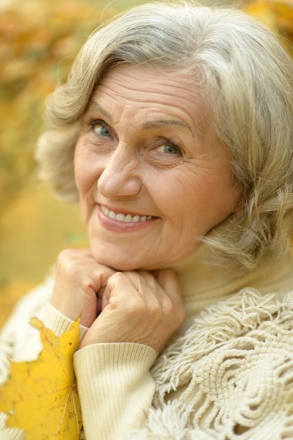 Happy beautiful senior woman in the autumn park