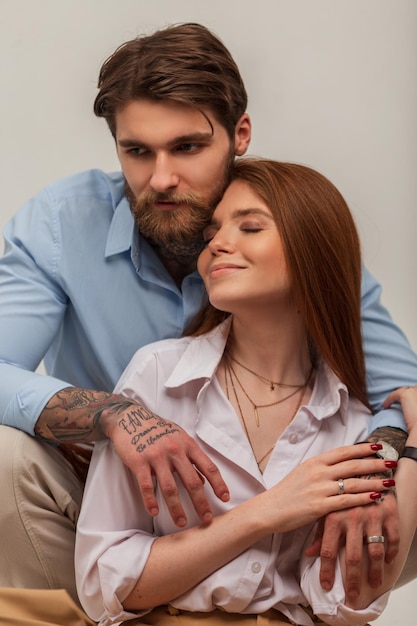 Happy beautiful tender young couple in the studio Beautiful happy tender redhaired girl and brutal hipster handsome man