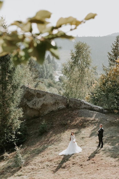 Photo happy beautiful wedding couple bride and groom at wedding day outdoors on the mountains rock.