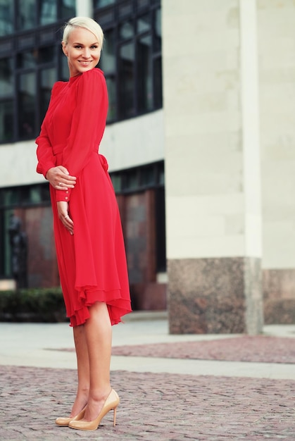 Happy beautiful woman in red summer dress walking and running joyful and cheerful smiling Summer day