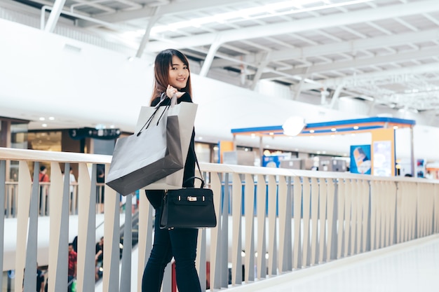 Happy beautiful woman with shopping bags stands at shop