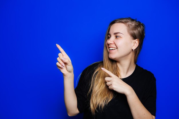 Happy beautiful woman without makeup in a black tshirt showing different emotions on a blue background Natural female beauty without cosmetics naturalness The concept of beauty