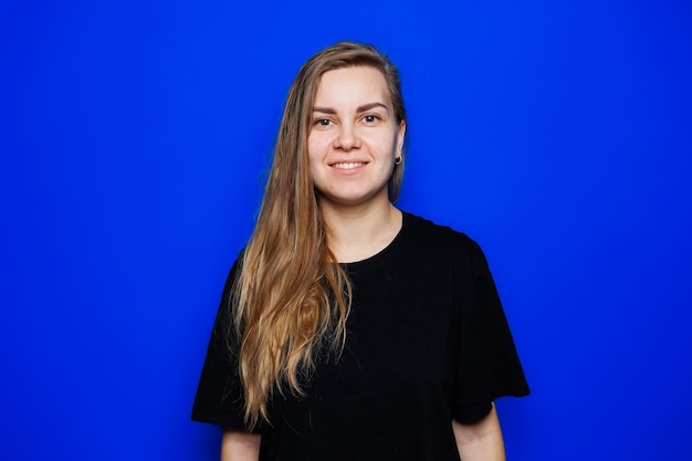 Happy beautiful woman without makeup in a black tshirt showing different emotions on a blue background Natural female beauty without cosmetics naturalness The concept of beauty