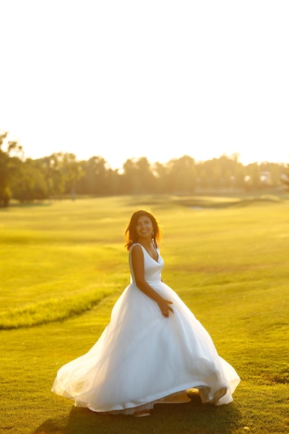 Happy beautiful young bride outside on a summer meadow at the sunset Wedding day