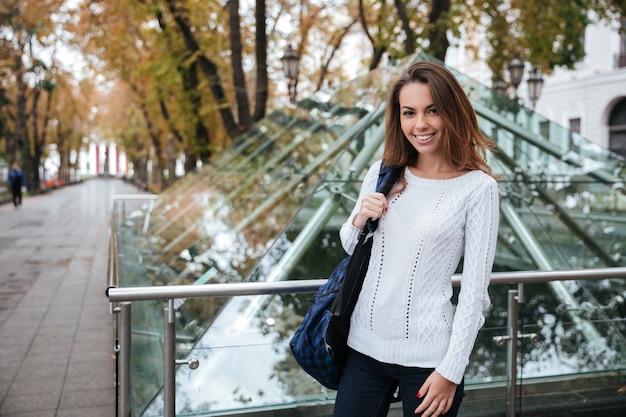 Happy beautiful young woman with backpack walking in the city