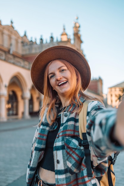 Happy beautiful young woman with gorgeous smile with teeth and blonde hair taking selfie in the old city of Krakow