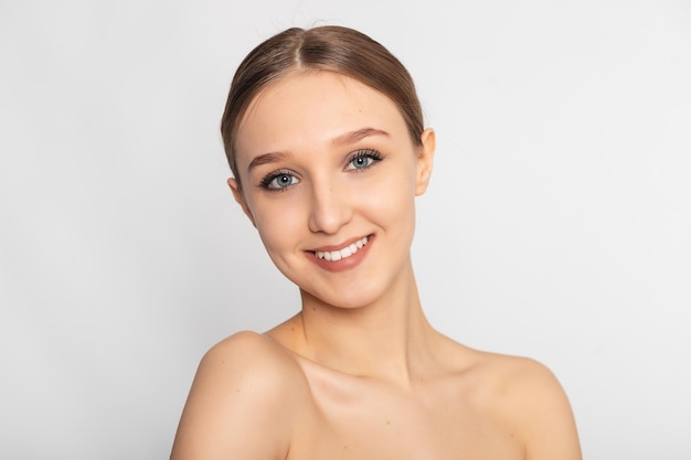 Happy beauty woman looking away isolated on background Cheerful young brunette with nude shoulder smiling after skin treatment Beautiful hispanic girl waiting spa therapy