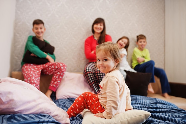 Happy big family is having fun together in bedroom. Large family morning concept. Mother with four kids wear pajamas in bed at home.