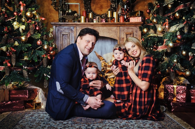 A happy big family with their children in the New Year's interior of the house by the fireplace next to the Christmas tree