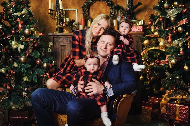 A happy big family with their children in the New Year's interior of the house by the fireplace next to the Christmas tree