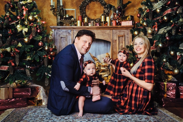 A happy big family with their children in the New Year's interior of the house by the fireplace next to the Christmas tree