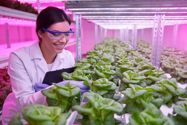 Happy biologist examining plants in laboratory