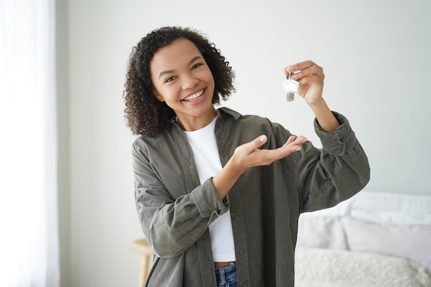 Happy biracial female buyer tenant of new home flat shows house keys Mortgage rental properties