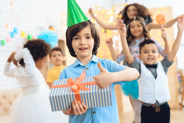 Happy birthday boy in green festive hat shows that he is happy with gift.