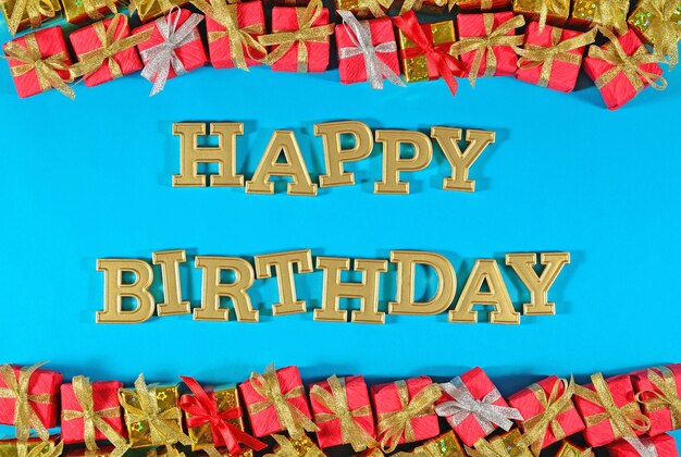 Happy birthday golden text and golden and red gifts on a blue background