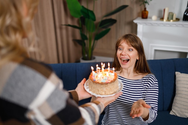 Happy birthday my sweetie Woman gives a cake with candles to her daughter