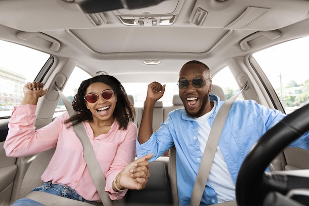 Happy black couple enjoying music driving luxury car