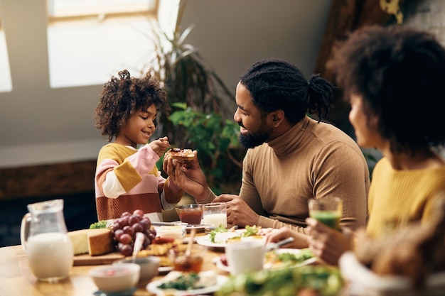 Happy black family eating jam and toasted bread for breakfast at home