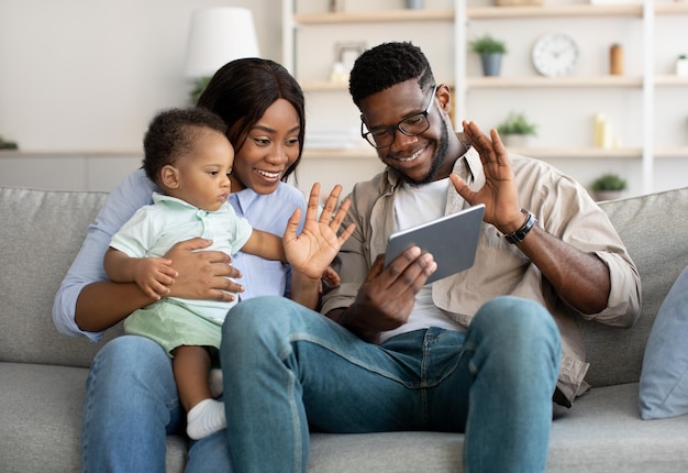 Happy black family having videocall using tablet waving hands