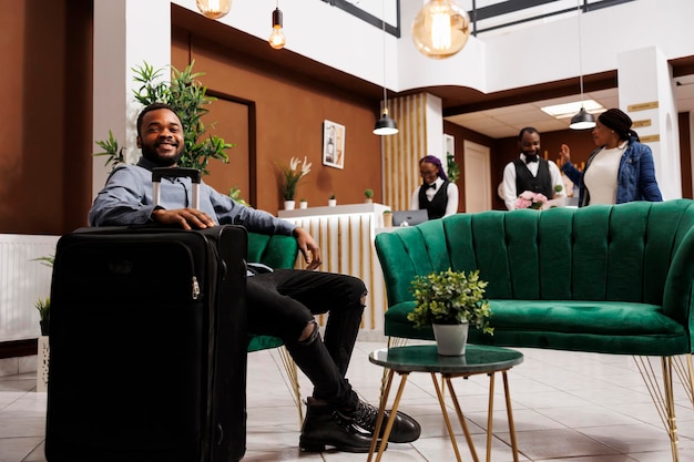 Happy black guy traveler at hotel lobby