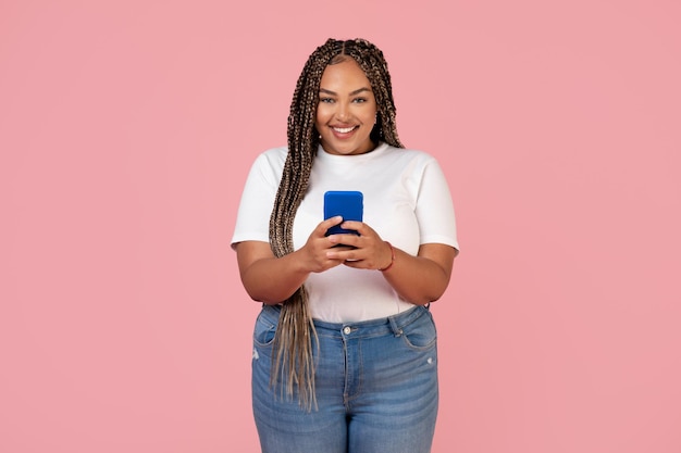 Happy Black Lady Using Phone Texting Standing Over Pink Background