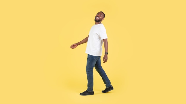 Happy Black Male Walking Posing In Studio Over Yellow Background