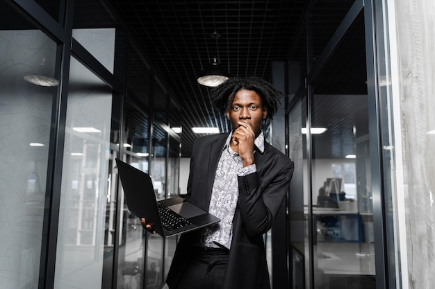 Happy black man clenched fists and rejoice finishing his online job on laptop. Working online in coworking space.