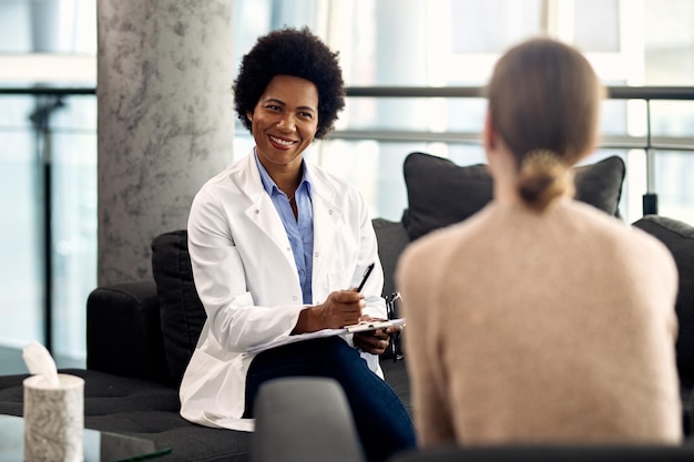 Happy black psychotherapist communicating with a patient during a session at the clinic