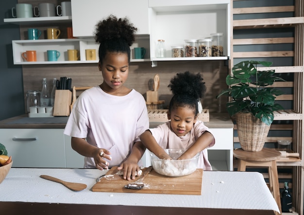 Happy black sisters threshing flour in the kitchen