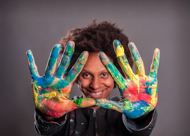 happy black woman with her hands painted on a gray background