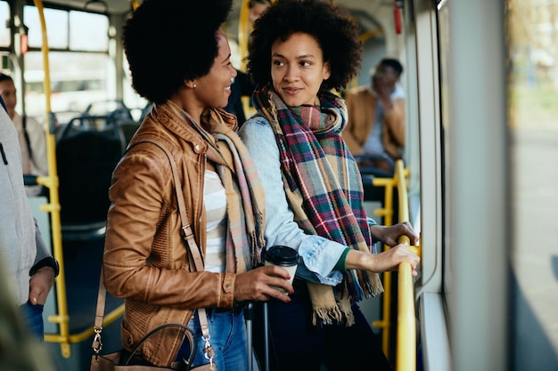 Happy black women talking while traveling by bus together