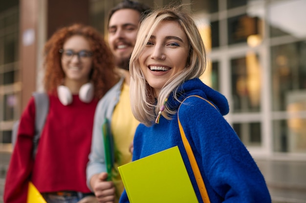 Happy blond woman near classmates