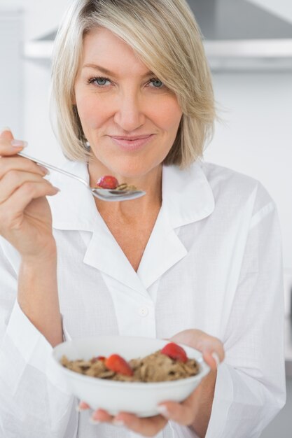 Happy blonde eating cereal for breakfast