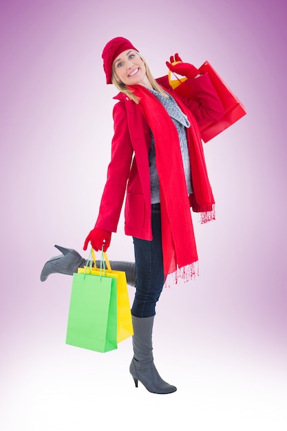 Happy blonde in winter clothes holding shopping bags