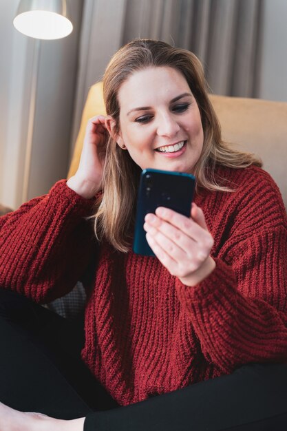 Happy blonde woman at home using smartphone