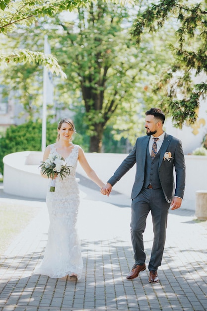 Happy Bosnian wedding couple walking in the park holding hands