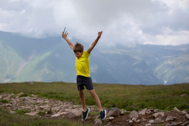 Happy boy against the backdrop of a mountain landscape joyfully jumping enjoying life