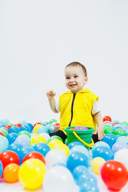 Happy boy in colorful balls in childrens playgroup the child smiles hiding in the balls