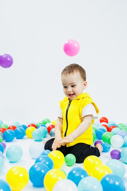 Happy boy in colorful balls in childrens playgroup the child smiles hiding in the balls