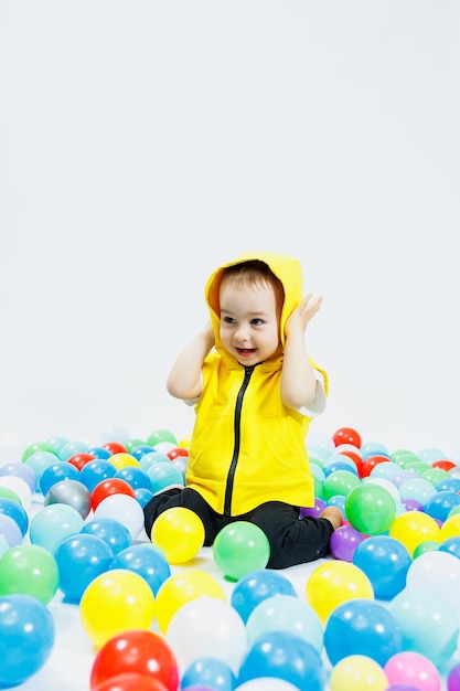 Happy boy in colorful balls in childrens playgroup the child smiles hiding in the balls