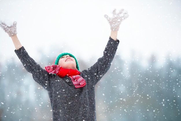 Happy boy under falling snow The child enjoys winter