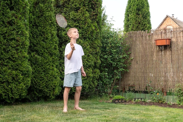 A happy boy holds a badminton racket in his hands outdoor activities