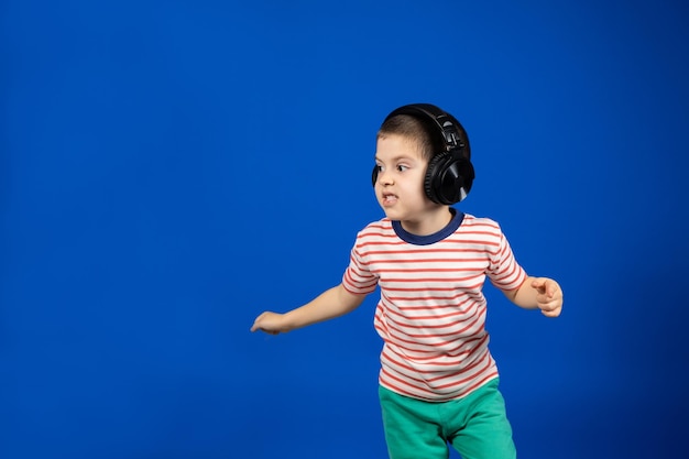 Happy boy in large wireless headphones runs and looks to the side