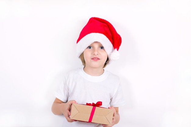 Happy boy in Santa red hat holding Christmas gift in hand. Christmas concept.