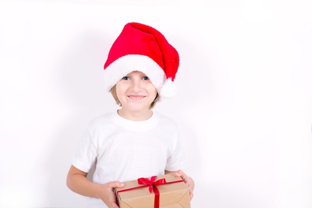 Happy boy in Santa red hat holding Christmas gift in hand. Christmas concept.