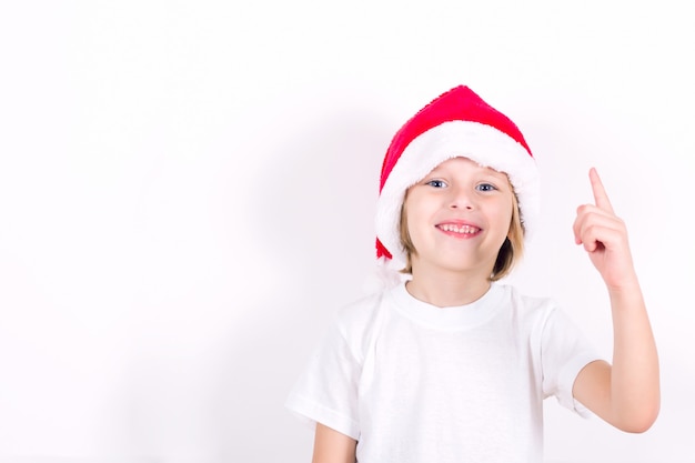 Happy boy in Santa red hat pointing with his finger. Concept for Christmas