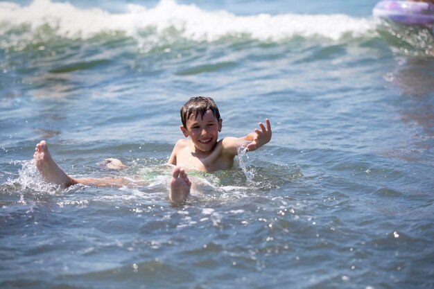 Happy boy swims in the sea plays with the waves Child on vacation at the seaside