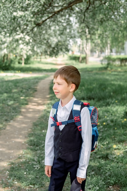 Happy boy with a backpack and a cap goes to school. The beginning of the new school year after the summer holidays.