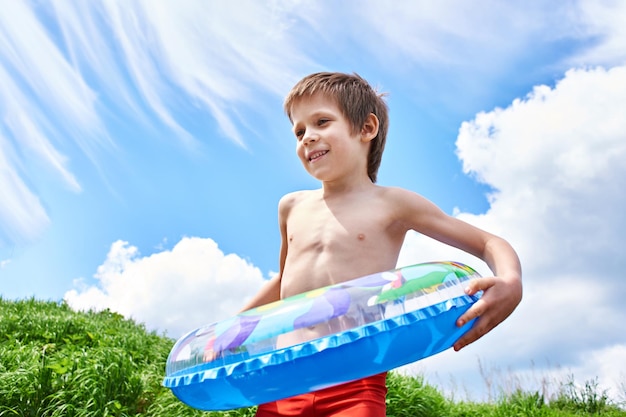 Happy boy with toy lifebuoy for swimming in summer day